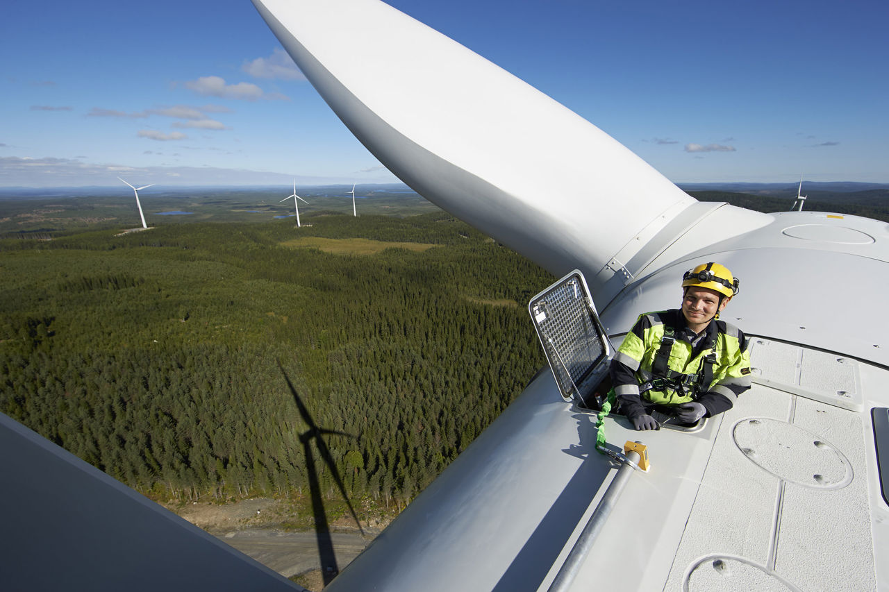 Man standing on top of wind mill