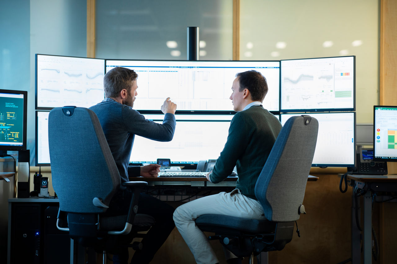 Two traders discussing in front of a computer